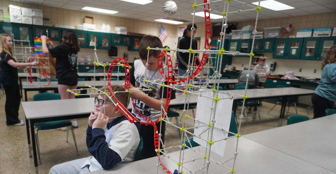 Two students work on building a roller coaster in a 6th grade class.