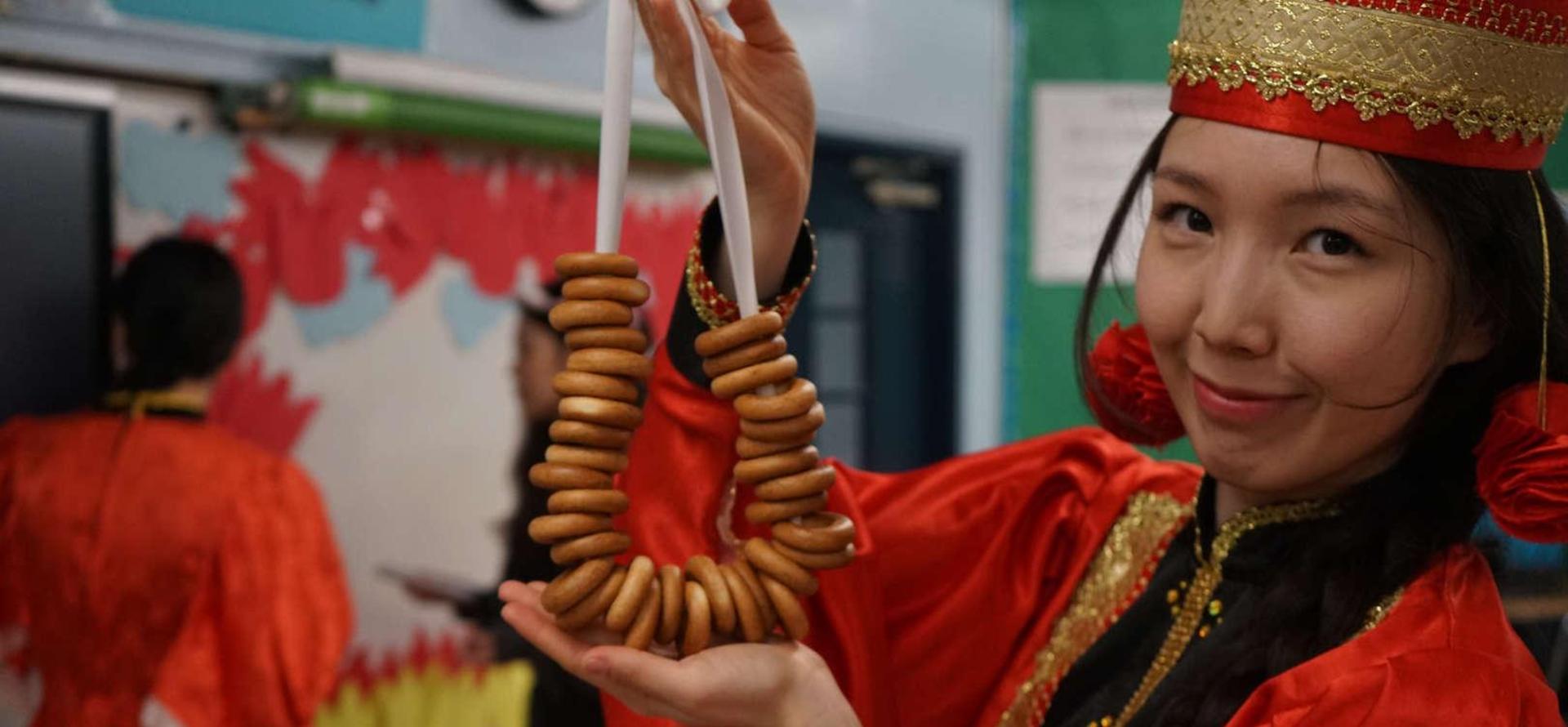 Person in traditional dress holding a necklace of wooden rings, smiling.