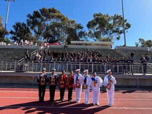 Student dressed in parade attire win and hold up their trophies in a group photo