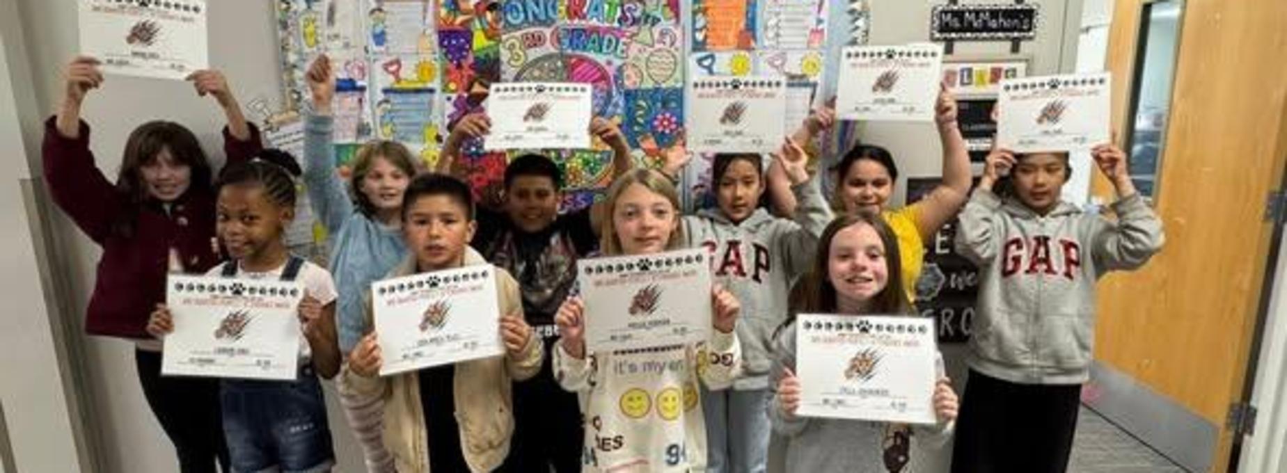 Students proudly holding achievement certificates in a colorful classroom.