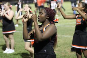 Cheerleader with red braids performing a cheer routine with teammates behind.