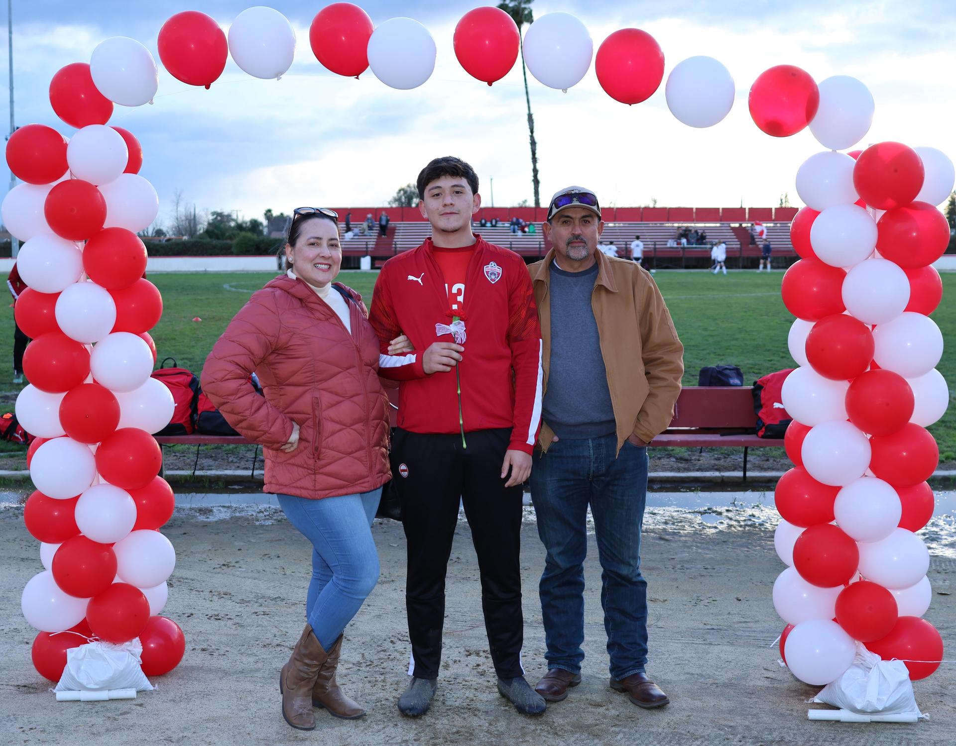 seniors and their escorts posing beneath a balloon arch