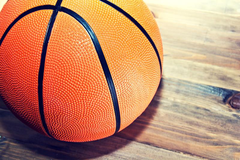 A basketball sits on a hardwood floor.