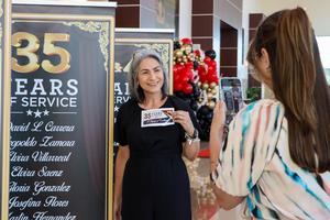 Photo of female taking a photo in front of 35 years of service banner