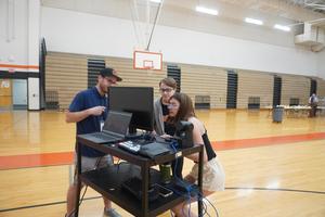 Teacher Derek Dean helps two students set up to film the 8th grade Breakfast of Champions.