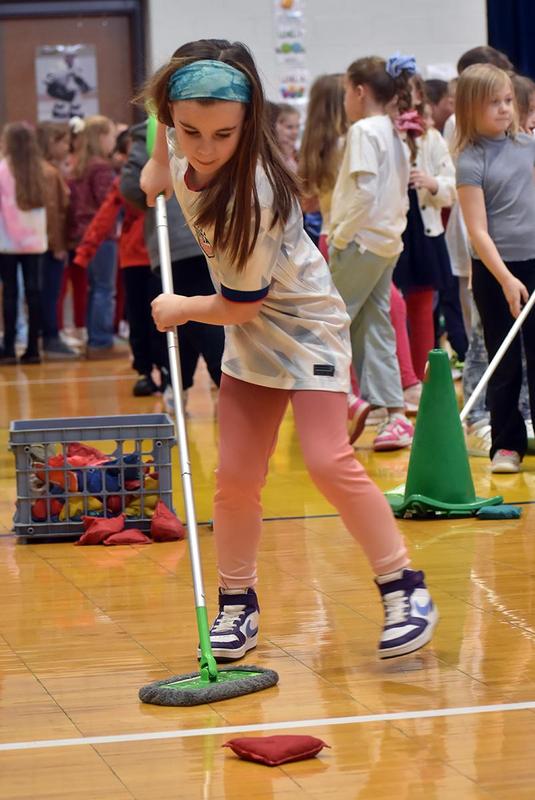 a girl pushing a bean bag with a dust mop