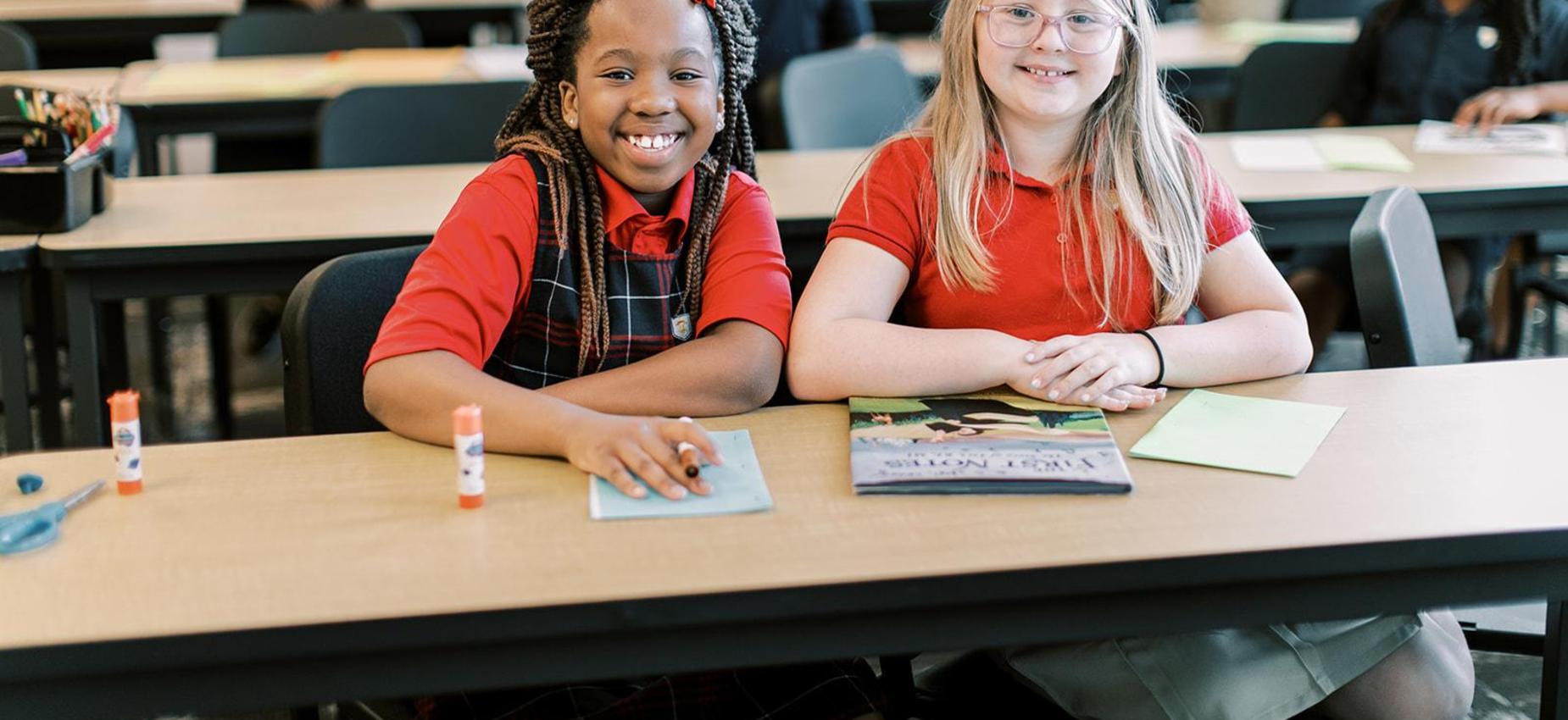 Two smiling students working together at a shared table