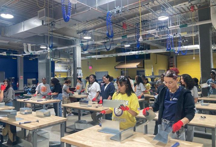A workshop scene with diverse individuals working on projects at tables.