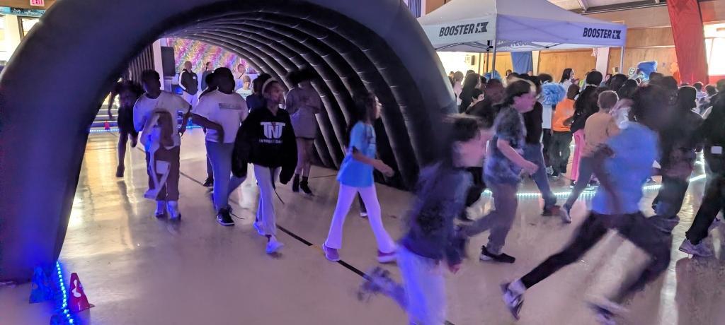 students running through an inflatable tunnel in school gym