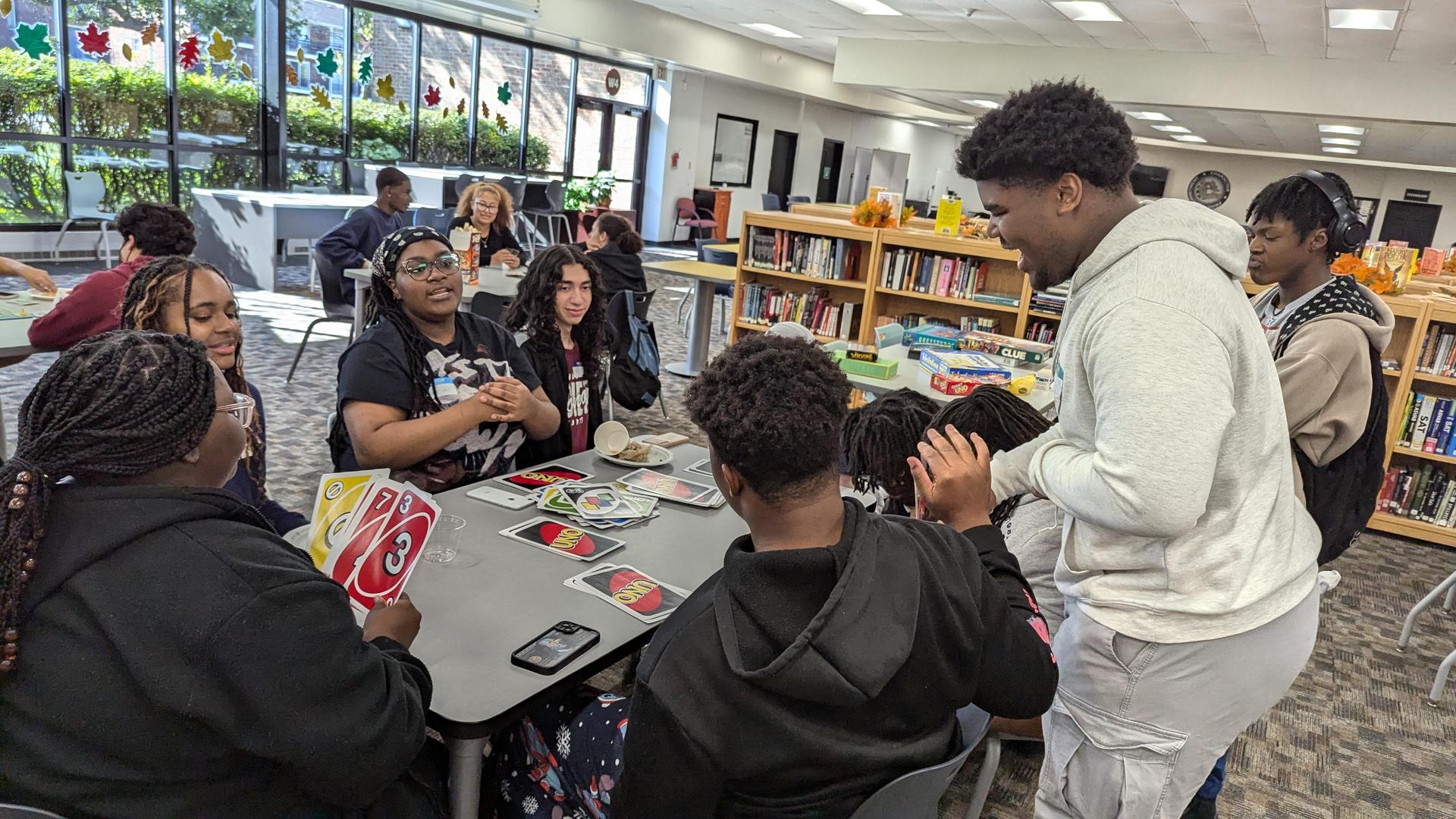 Several teenagers gathered around a table playing board games