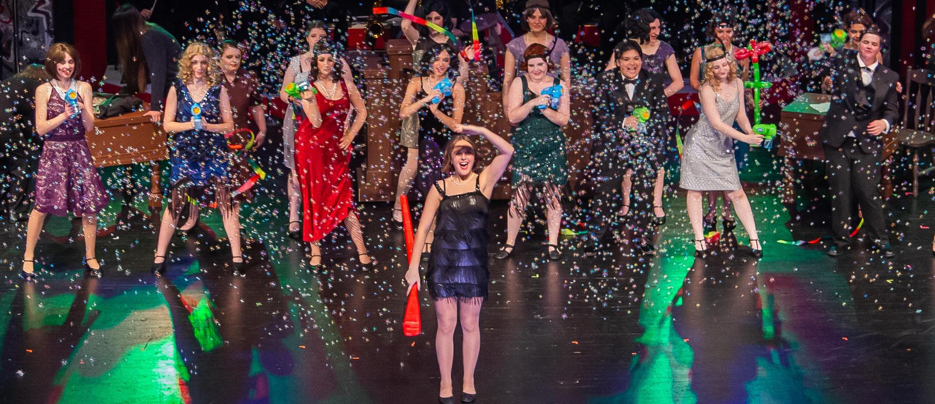 Chicago student musical with flapper outfits on girls on dark stage and confetti