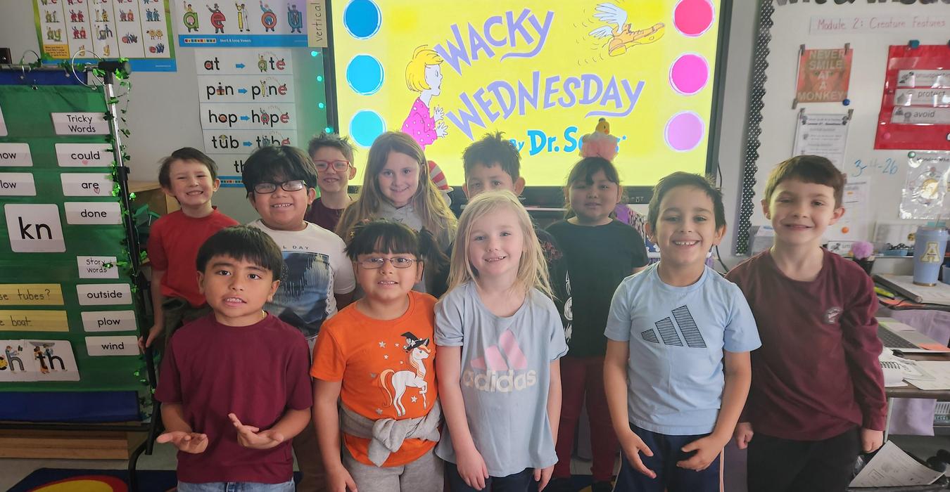 A group of children smiling in front of a screen labeled 'Wacky Wednesday'.