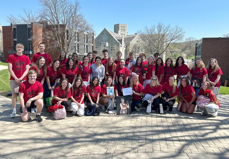A large group of students in red shirts posing together outdoors.