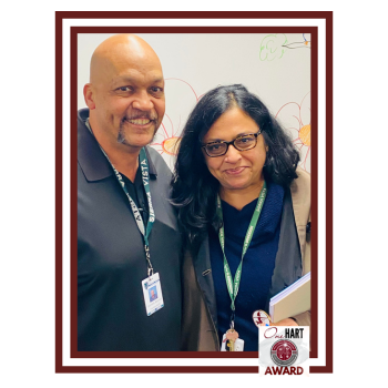 A man and a woman posing together, smiling, with a colorful background.