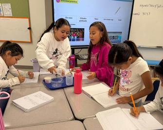 Five girls collaborating on an activity at their desks.