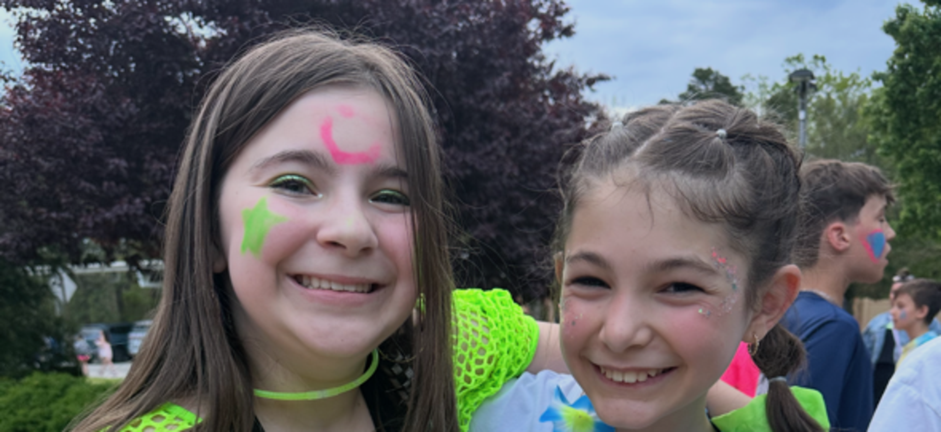 Two girls smiling, wearing brightly colored outfits and accessories.