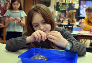 A student putting tiny beads on a wire