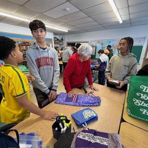 Students in a classroom organizing and folding fabric.