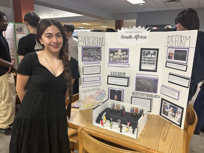 Smiling students stand with school projects