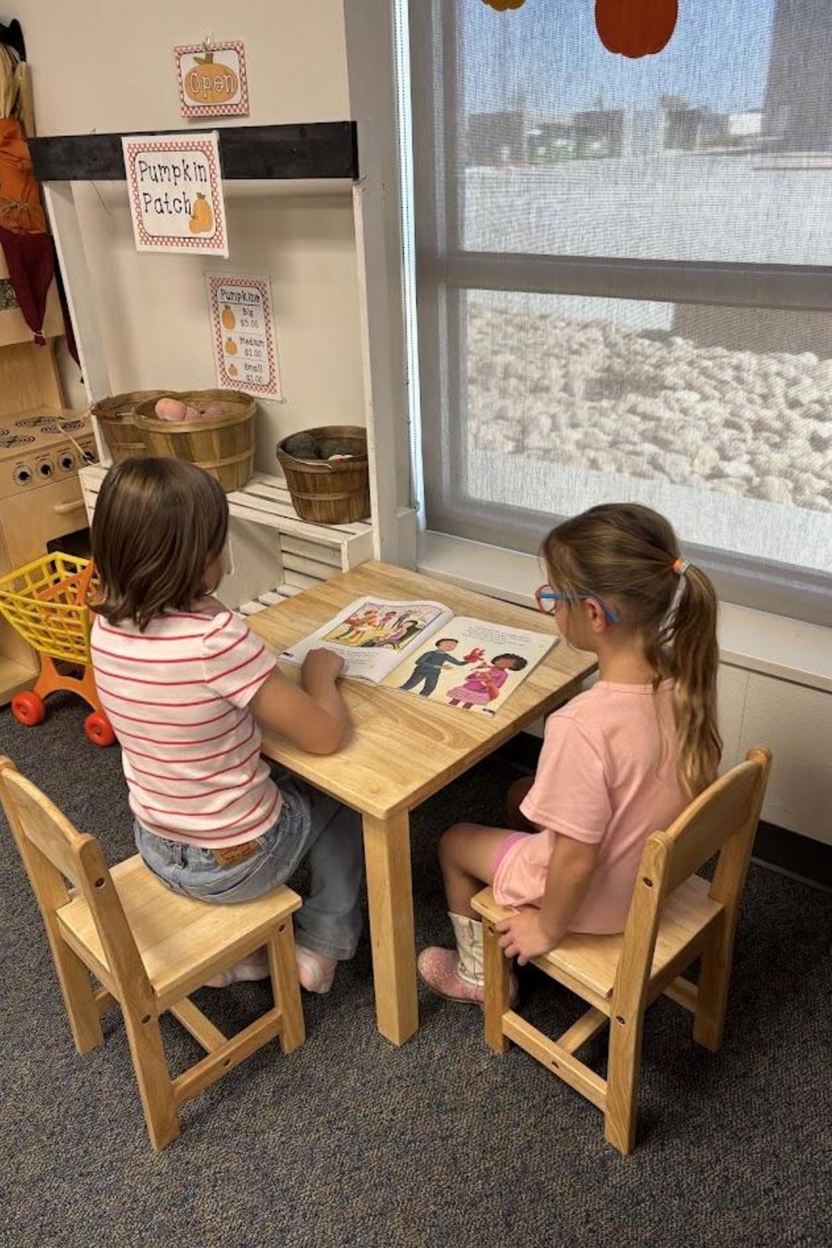 Second grade student reading to preschool student