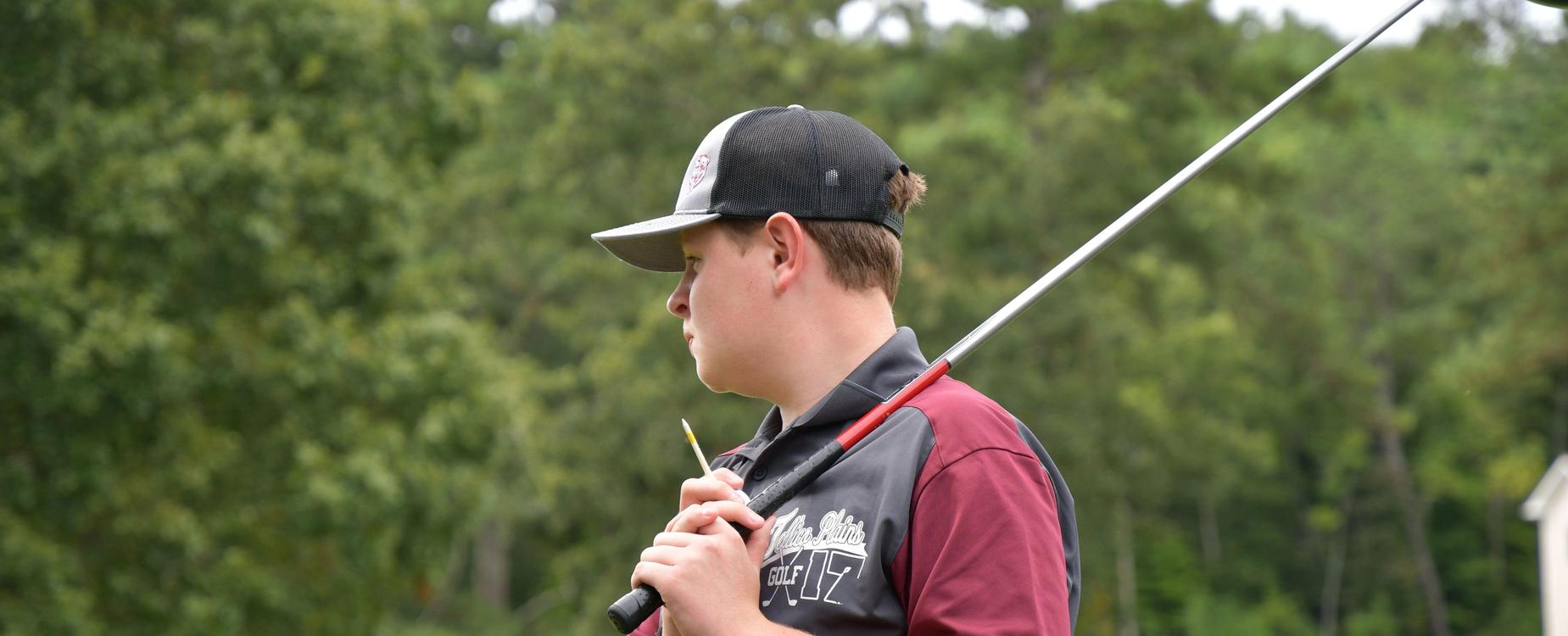 Young golfer holding a club, focused on play against a green background.