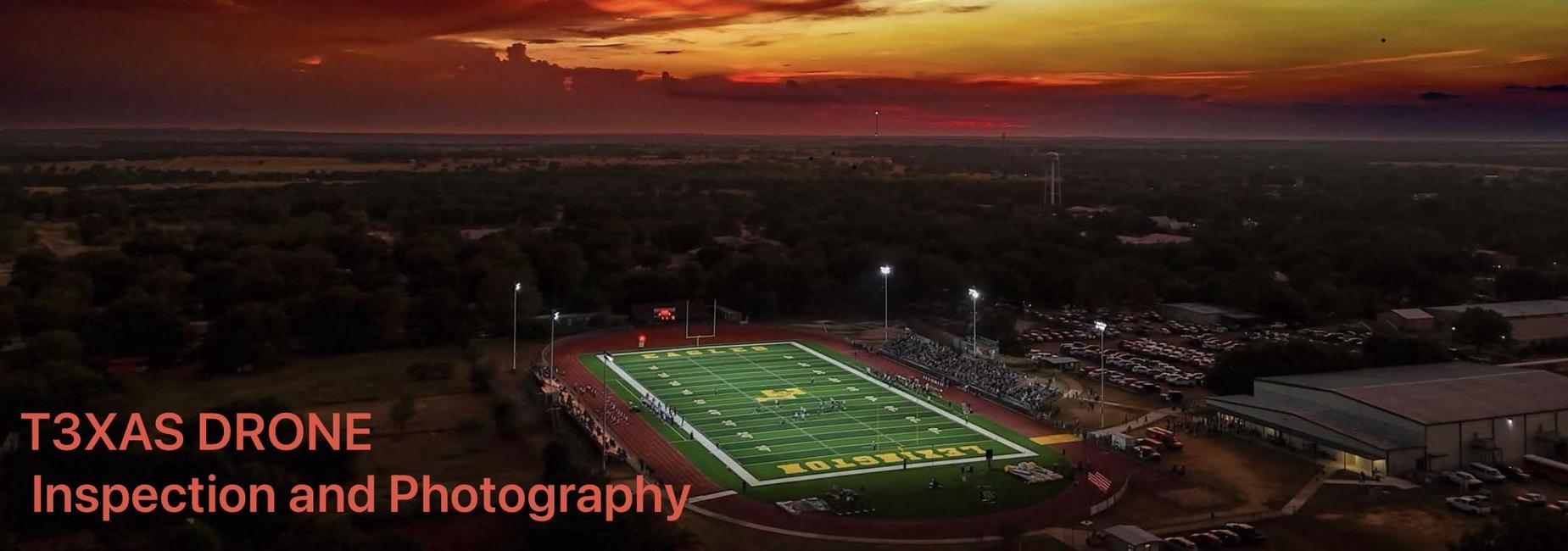 Vibrant sunset over a football field and surrounding landscape.