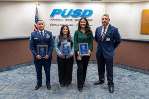 SSgt Jose Ortiz, Krystal Cortez, and Kimberly Agustin hold their recognition plaques at the PUSD Board meeting alongside a district administrator.