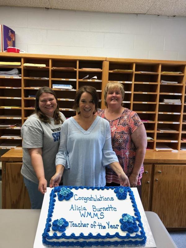 Mrs Ray, Mrs Burnette and Dr Gardner holding cake.