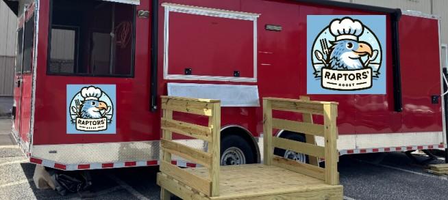 Red food truck with an eagle logo and a wooden steps platform in front.