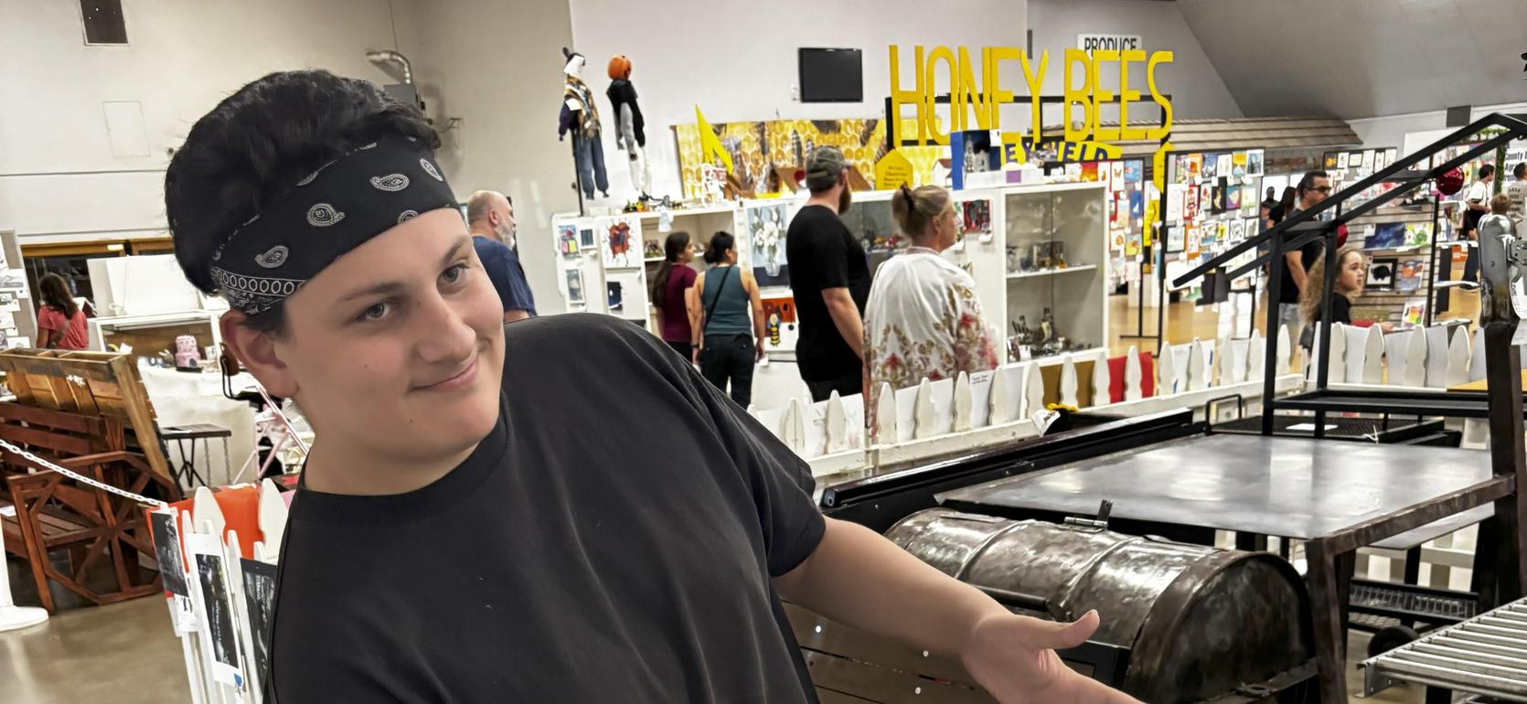 A person in a black shirt posing in front of a display of photos and furniture.