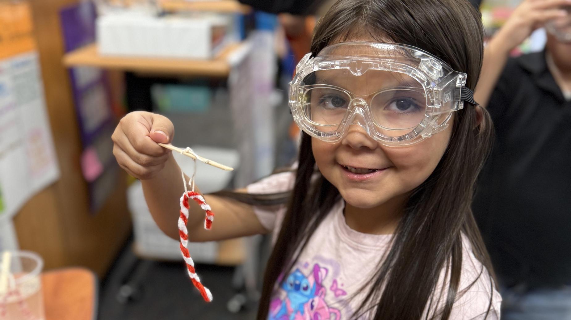 Student showing her science experiment with candy cane colored and shaped pipe cleaners