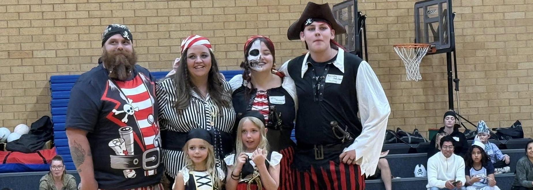 Group of pirates in costumes posing together happily at an event.