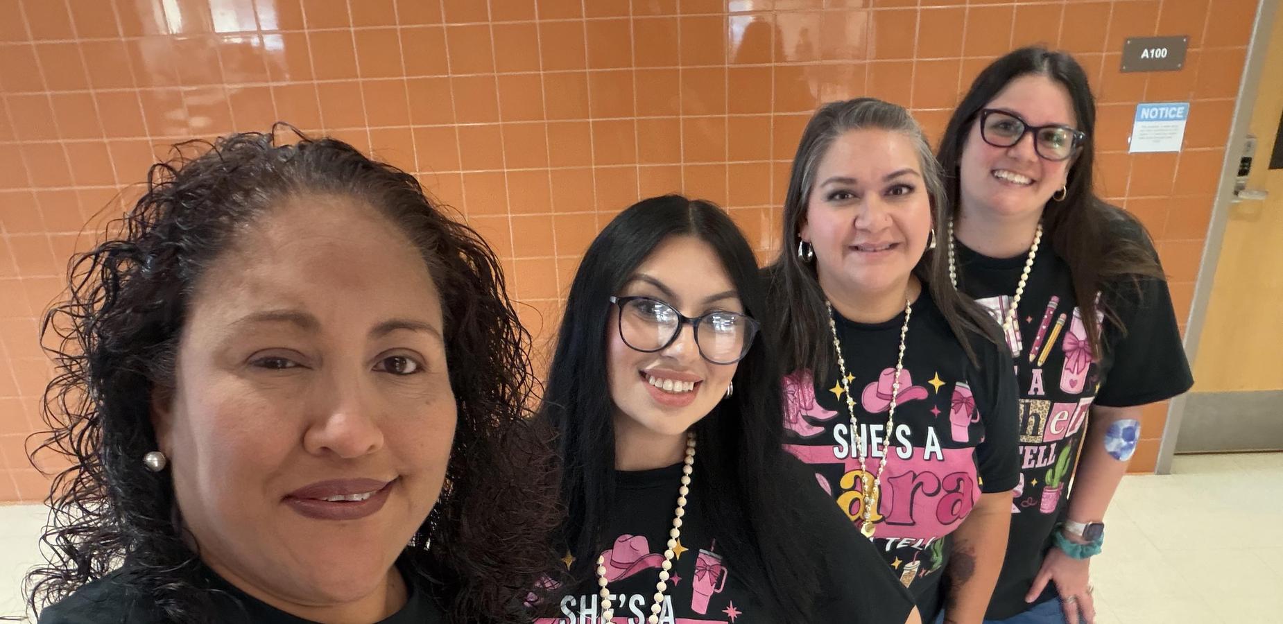 Four women in matching shirts pose together, showing off their styles and smiles.