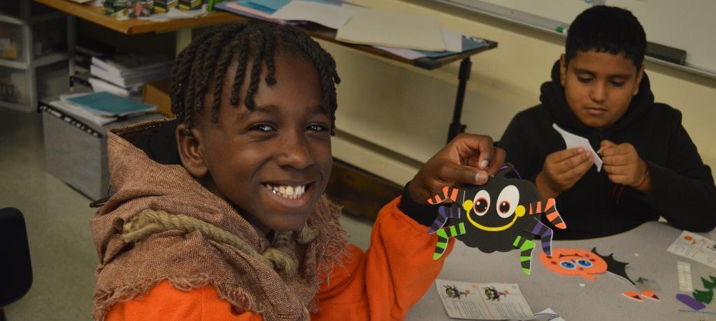 boy shows off his finished paper spider craft