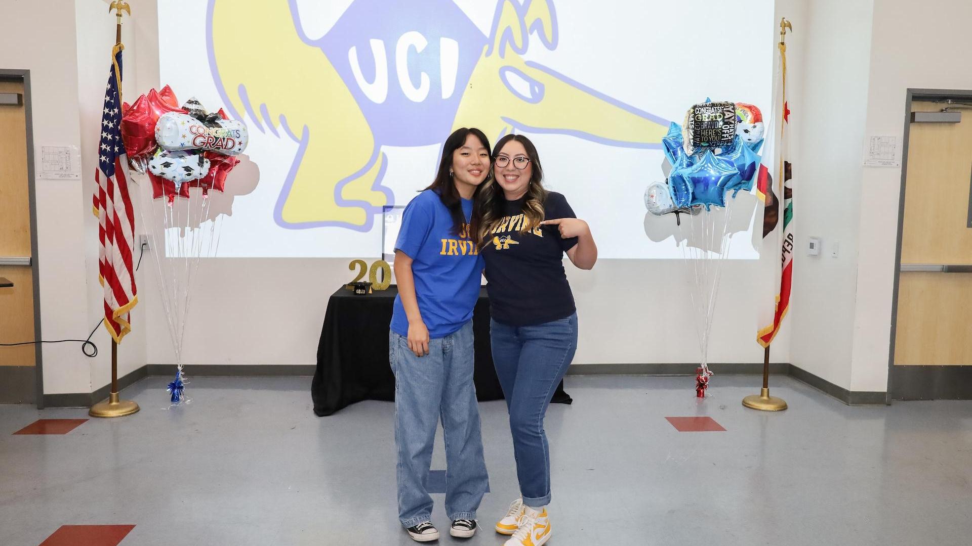Two women wearing university shirts at a celebration.