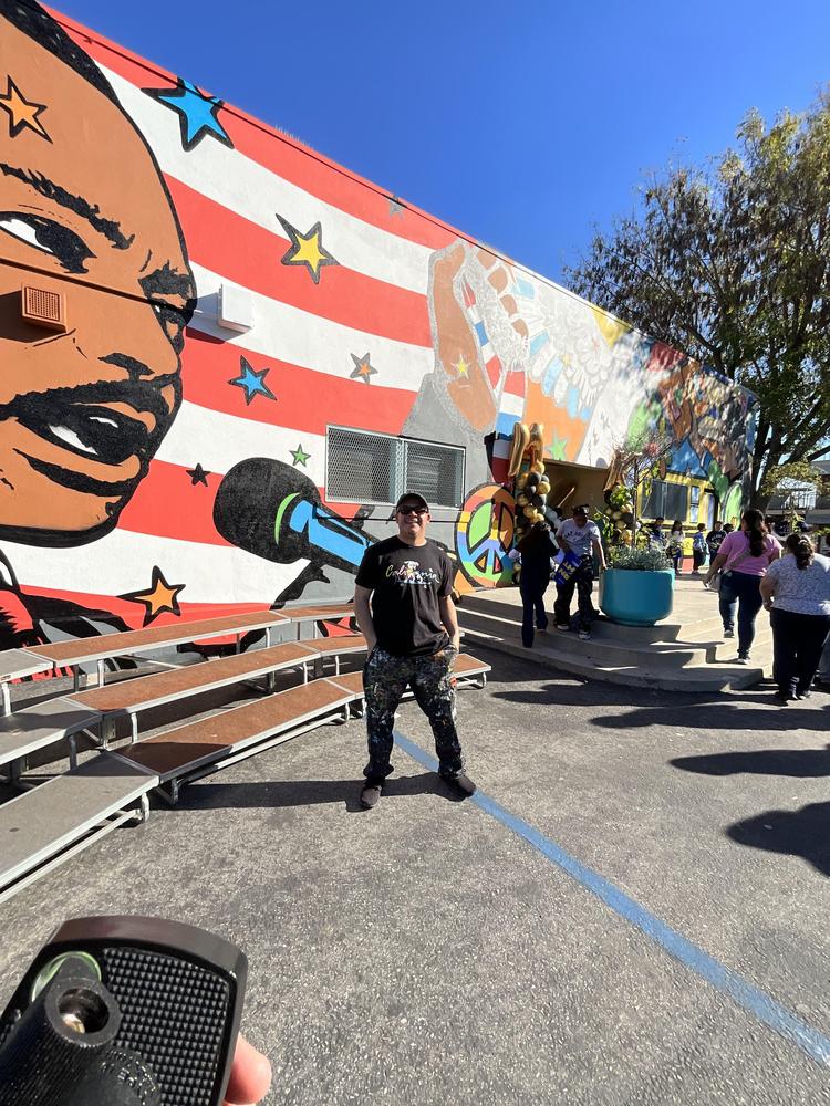 The mural artist Bumblebee Loves you next to the mural