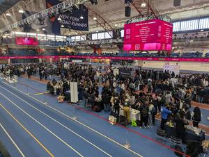 Crowd of people interacting at a busy event inside a large venue.