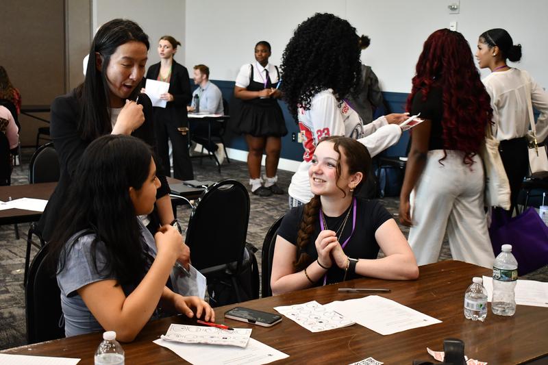 Students sit at a table with an adult volunteer
