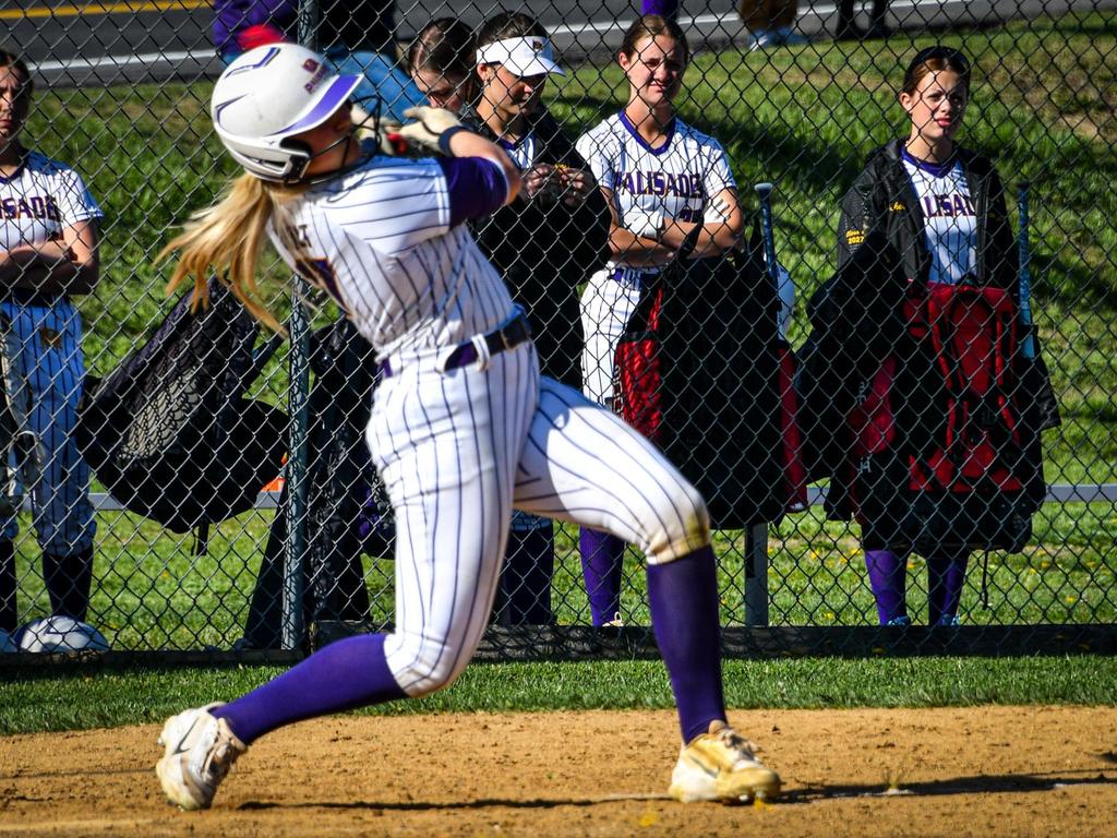 A softball player swinging her bat.
