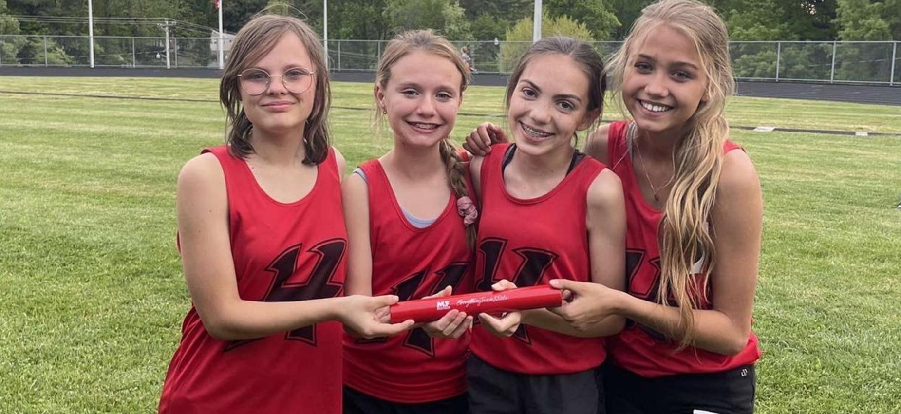 Four girls stand beside a track.