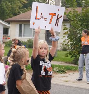 An elementary student holds up a sign "LOVE TK" during the parade.
