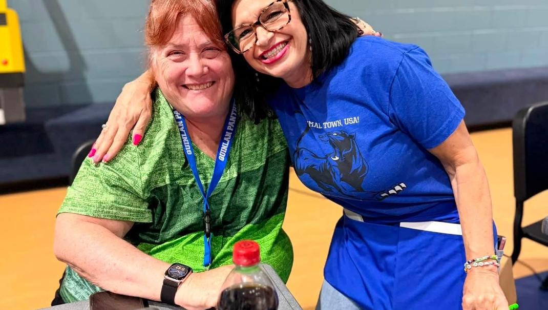 Two women smiling together at a school event.