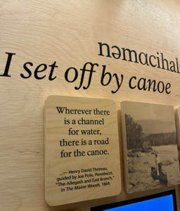 Wooden sign with text about canoeing, accompanied by a quote from Thoreau.