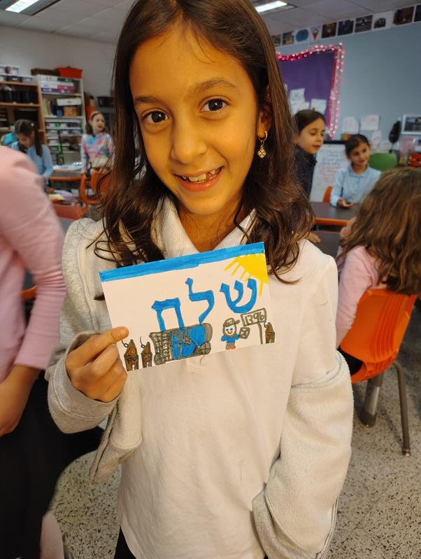 a second grade student holds up a shorash card