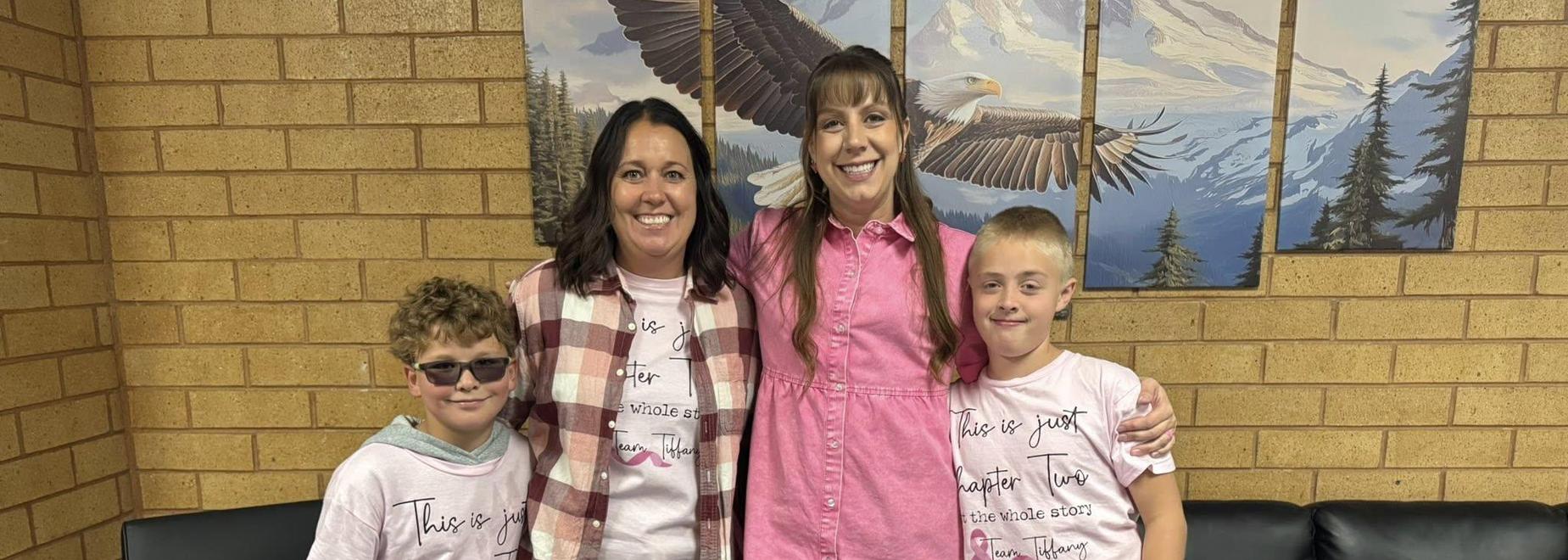 A group photo of four people wearing matching t-shirts, smiling together.