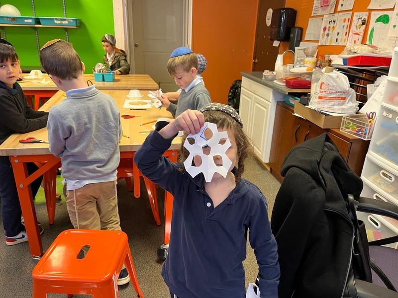 A first grade boy shows off his snowflake