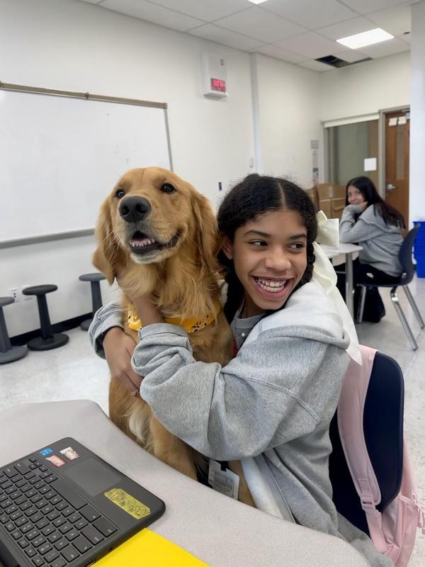 therapy dog with student hugging him