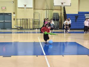 A girl chases a balloon using an umbrella.