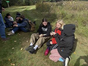 Group of children sitting on grass, engaging in conversation and activities.