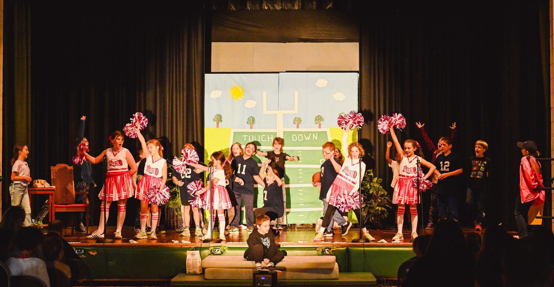 A lively school performance with students cheerleading on stage.
